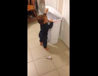 Baby struggles to throw sock in bin