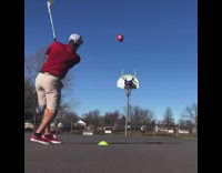 Hitting football onto basket with golf club