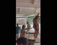 Two women in bikini twerks on top of the table