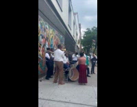 Instrument band perform on street beside mural