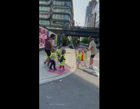 Line of toddlers cross street with neon vests 
